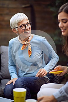 Senior mother and adult daughter sitting  outdoors at home