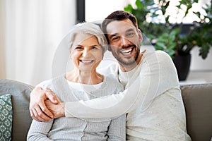 Senior mother with adult son hugging at home photo