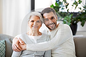 Senior mother with adult son hugging at home