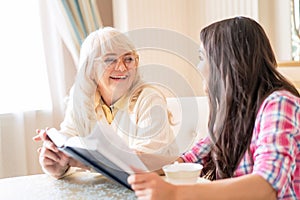 Senior mother and daughter read a book over a cup of tea photo