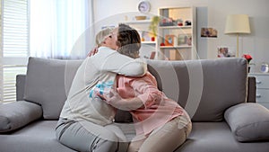 Senior mother embracing adult daughter, holding gift box, love and care concept