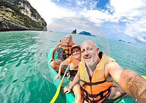 Senior mother and father with son taking selfie at kayak excursion in Thailand - Adventure travel in south east asia