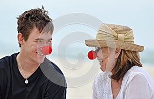 Senior mother & grown son in red noses laughing together