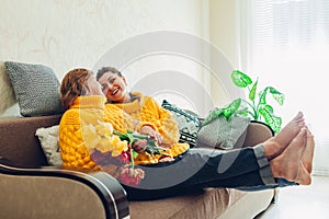 Senior mother and her adult daughter sitting on couch and laughing at home. Mother`s day concept