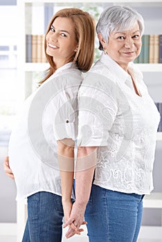 Senior mother and pregnant daughter smiling