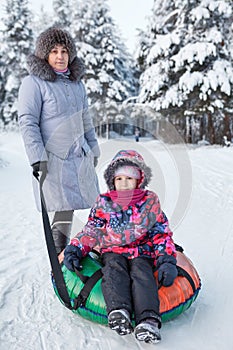 Senior mother and young child portrait with snow tubing
