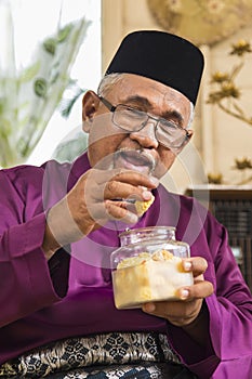 Senior Muslim man eating traditional Malay cookie
