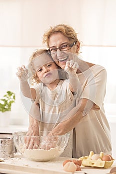 Senior nanny standing behing child during cooking