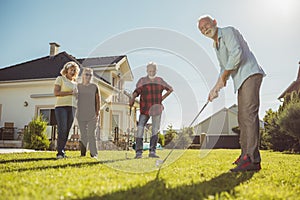 Senior neighbors having fun playing mini golf in the backyard