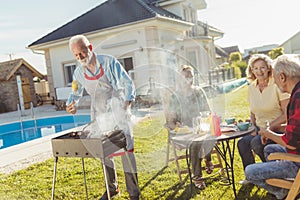 Senior neighbors making barbecue in the backyard