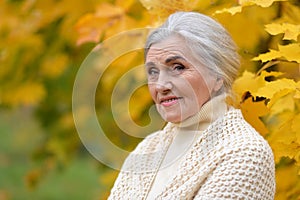 Senior nice woman walking in the park in autumn.