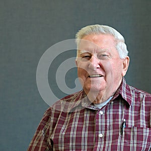 Senior octogenarian old man in plaid with gray background