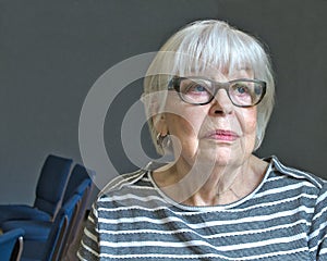 Senior octogenarian woman in striped top with gray background