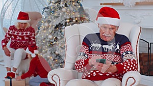 Senior old grandfather man buy Christmas gift presents doing online shopping on smartphone at home