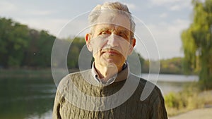 Senior old gray-haired man looking at camera, serious happy elder mature grandfather with toothy smile posing for close