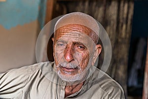 A senior old homeless man is staring and his expression is very painful