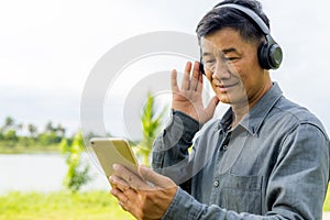 Senior old male wearing earphone and listening music.