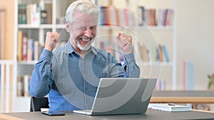 Senior Old Man Celebrating Success on Laptop in Library