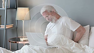 Senior Old Man with Laptop having Back Pain in Bed