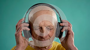 Senior old man listening to favourite music or song through big headphones, enjoying relaxed
