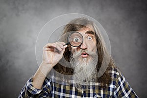 Senior old man looking through zoom magnifying gla
