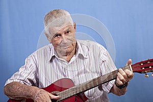 Senior old man playing a red guitar