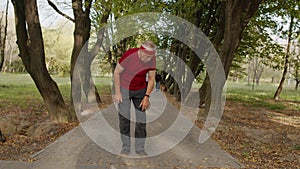 Senior old man running in park and using smart watch, tracking result during fitness workout