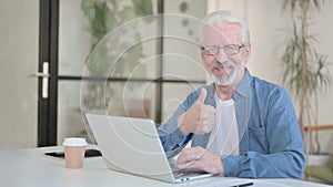 Senior Old Man showing Thumbs Up while using Laptop in Office