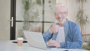 Senior Old Man showing Thumbs Up while using Laptop in Office