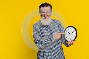Senior old man showing time hour on wall office clock, ok, thumb up, approve, hurry up, deadline