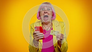 Senior old stylish granny woman using credit bank card and smartphone purchases online shopping