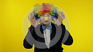 Senior old woman clown in colorful wig smiling, making silly faces, fool around