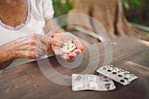 Senior old woman hands holding vitamins pills outdoors in garden. Healthcare aged people concept