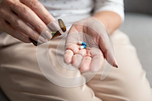 Senior woman holding pills capsules on hand, close up view