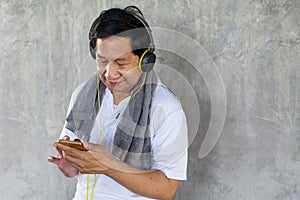 Senior older man taking a break from  workout  listening music with headphones and phone relaxing in gym. aged . Old male .Mature