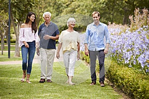 Senior Parents With Adult Children On Walk In Park