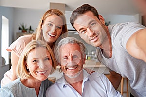 Senior Parents With Adult Offspring Posing For Selfie At Home photo