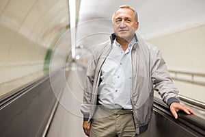 Senior passenger walks along travelator in an underground metro