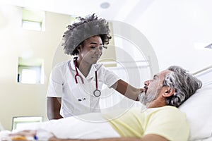 Senior patient on bed talking to African American female doctor in hospital room, Health care and insurance concept. Doctor