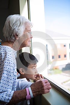 Senior patient and boy looking out from the window