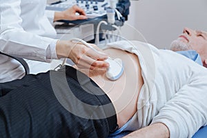 Senior patient getting ultrasound scanning of abdomen in the clinic