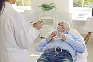 Senior patient listening to doctor lying on bed in hospital office during medical check-up