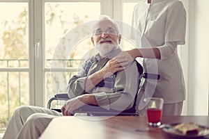 Senior patient in nursing home with helpful nurse in white uniform