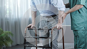 Senior patient of nursing home moving with walking frame and nurse support