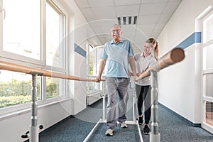 Senior Patient and physical therapist in rehabilitation walking exercises