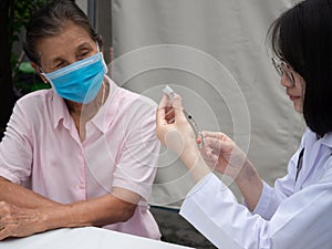 Senior patient  vacination in a inflatble hospital, doctor prepare vaccine and syrign for a woman