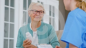 Senior patient woman with glasses holds pills bottle listening to doctor explanations in room