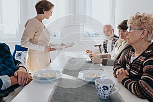 Senior patients and nurse in local nursing home during dinner time