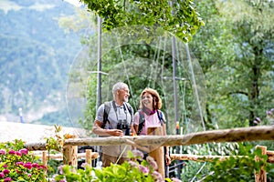 A senior pensioner couple with binoculars hiking, walking.