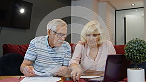 Senior pensioner couple checking and calculating domestic bills bank loan payment doing paperwork